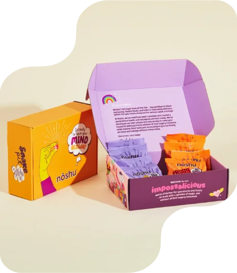 Colorful influencer snack boxes—orange and purple box with bold slogan and hand graphic printing, plus open purple box with rainbow print and snack packs inside.