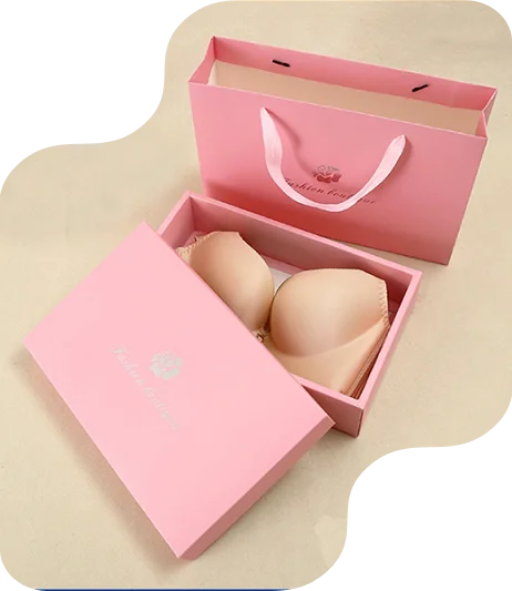 Elegant pink gift two piece rigid box with floral logo and “Fashion Bra” text on lid, paired with matching branded shopping bag for retail or gifting. Inside: beige bra.