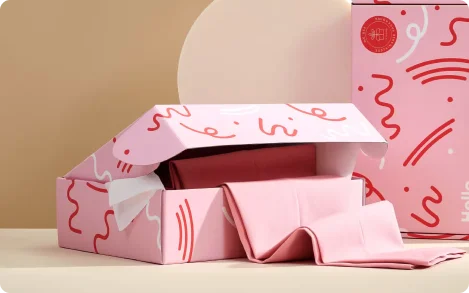 Custom pink influencer box with red and white abstract design, white “hello” text, circular red seal, and folded fabric inside for premium unboxing.